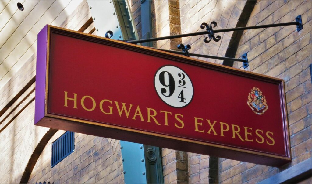Un panneau rouge et or « Poudlard Express » avec l'emblème emblématique « 9 3/4 » orne un mur de briques, invitant les fans dans l'empire magique enchanteur d'Harry Potter.
