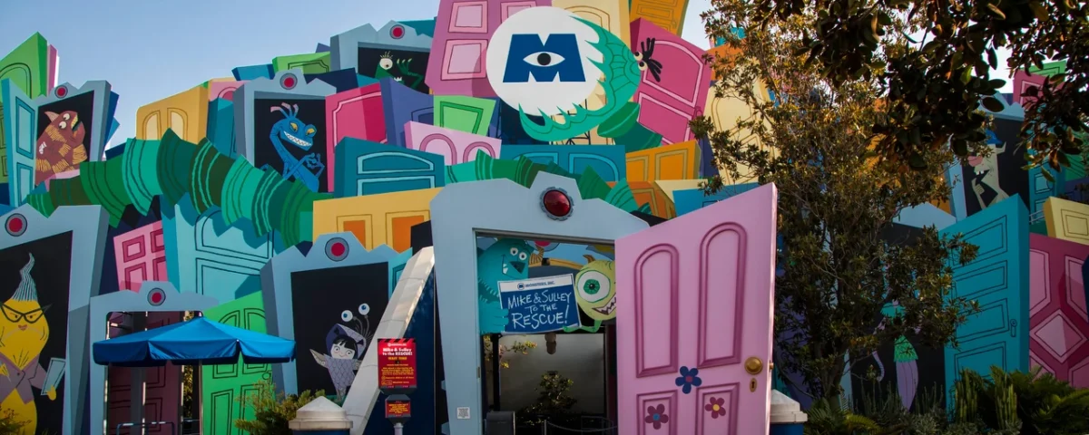 Une façade colorée et caricaturale représentant des éléments de construction surdimensionnés comme des fenêtres et des portes, conçue de manière créative comme l'entrée de l'attraction Monsters Inc : Mike & Sulley to the Rescue!".
