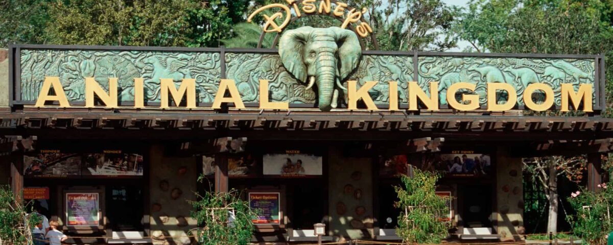 L'entrée du parc à thème Disney's Animal Kingdom, avec un grand panneau vert avec le nom du parc et une sculpture d'éléphant au centre, entourée d'une verdure luxuriante.