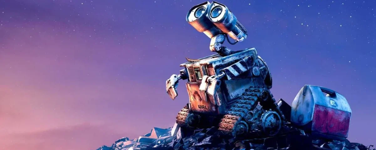 Une photo du robot animé Wall E assis sur un gros tas d'ordures sous un ciel étoilé au crépuscule, l'air pensif et curieux.