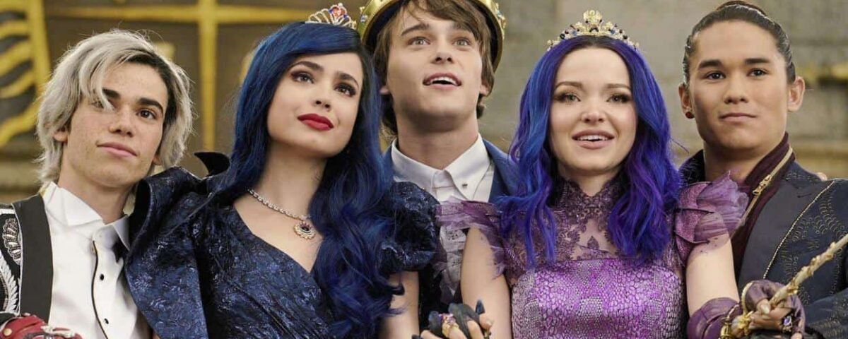 Cinq jeunes acteurs se faisant passer pour des descendants de membres de la famille royale dans une scène de film fantastique, portant des costumes et des couronnes ornés, dans une somptueuse salle dorée, exprimant une joyeuse camaraderie.