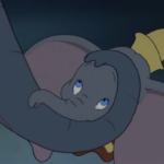 Une image de dessin animé de Dumbo, le petit éléphant des chansons de Disney, l'air triste et reposant sa tête et sa trompe sur ses jambes croisées, avec un petit chapeau jaune sur la tête.