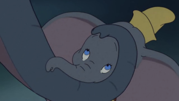 Une image de dessin animé de Dumbo, le petit éléphant des chansons de Disney, l'air triste et reposant sa tête et sa trompe sur ses jambes croisées, avec un petit chapeau jaune sur la tête.