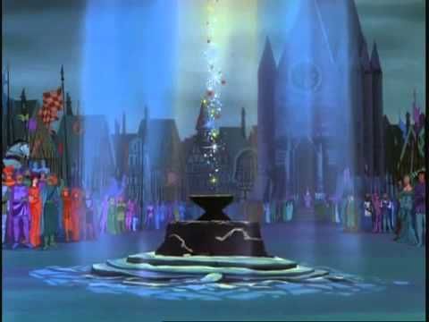Image tirée d'un film d'animation Disney montrant une place publique colorée et animée au crépuscule avec des citoyens habillés en costumes d'Halloween. Un faisceau rayé en forme de serpent s’élève vers le ciel depuis une petite fontaine.