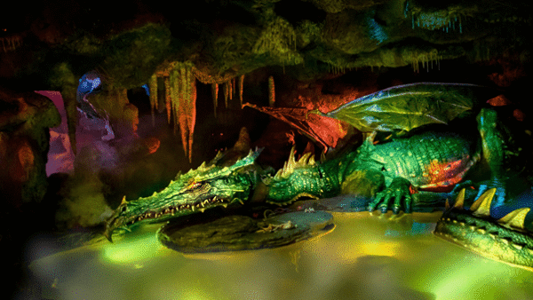 Un dragon vert dans une grotte sombre avec des personnages mystérieux.