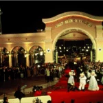 Entrée des studios Walt Disney avec des personnages en costume saluant les invités sur un tapis rouge lors d'une soirée.