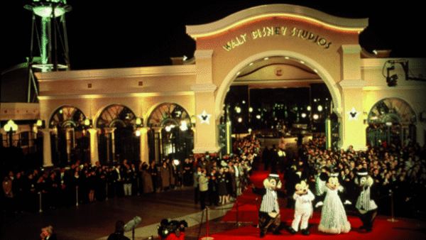 Entrée des studios Walt Disney avec des personnages en costume saluant les invités sur un tapis rouge lors d'une soirée.