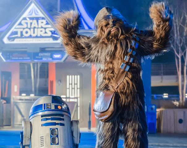 Personnages Chewbacca et R2-D2 à l'attraction Star Tours, avec Chewbacca posant les bras levés et R2-D2 à côté de lui.