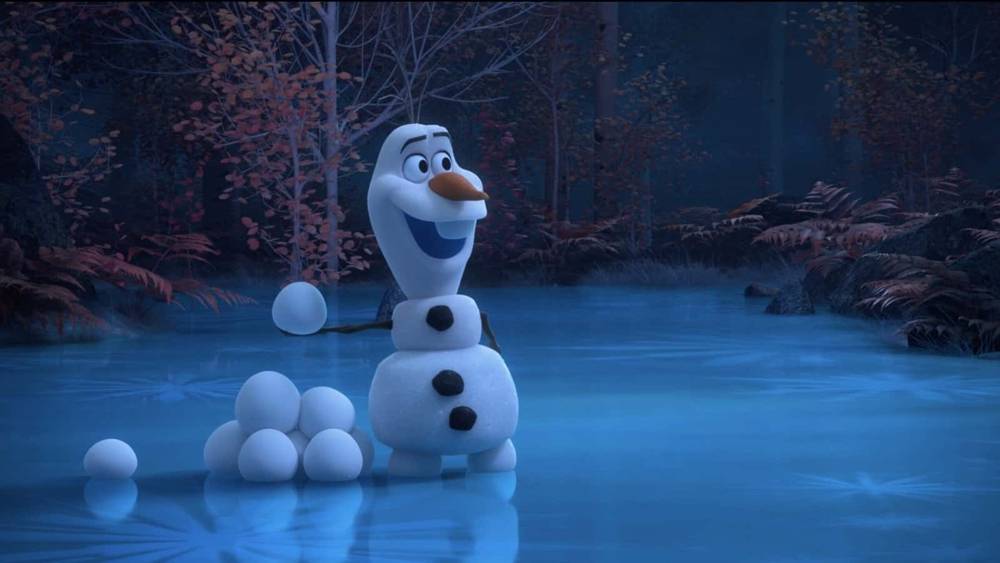 Olaf, un personnage Disney de La Reine des Neiges, se tient souriant sur un lac gelé entouré d'une forêt crépusculaire aux feuilles aux couleurs de l'automne.