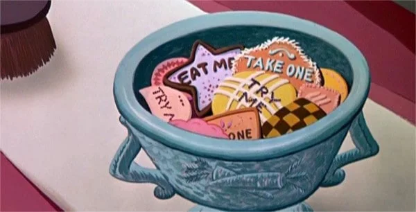 Un bol rempli de biscuits colorés et fantaisistes, chacun formé et décoré différemment avec des messages comme « mange-moi » et « prends-en un », tirés d'un film Disney.