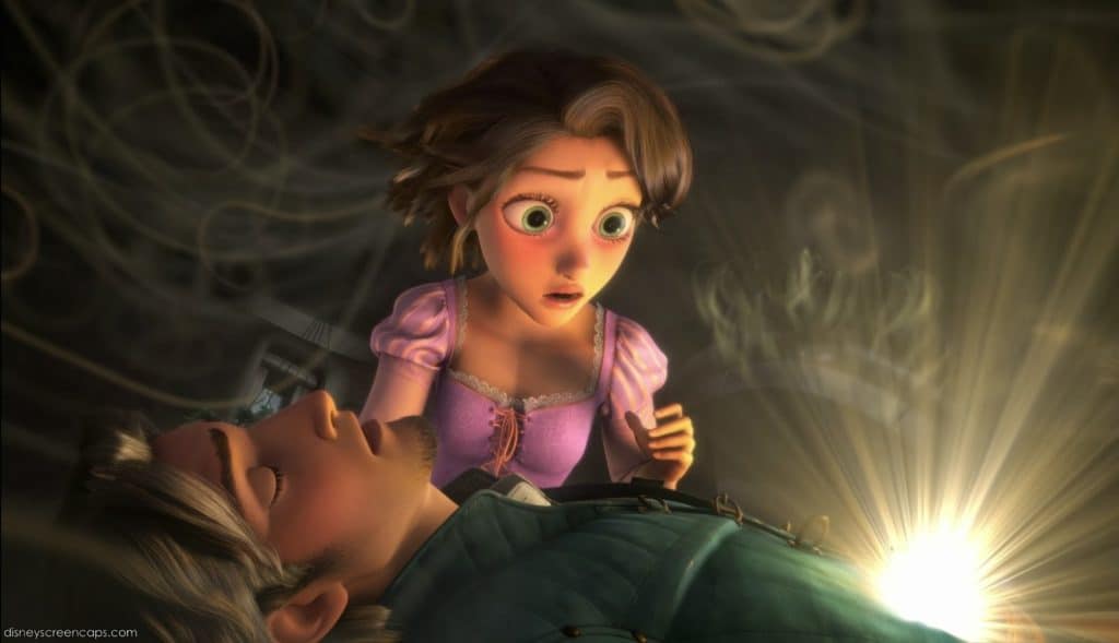 Une scène d'un conte de fées animé montrant une jeune femme inquiète aux cheveux bruns regardant un jeune homme allongé inconscient, avec un élément magique brillant près de sa poitrine.