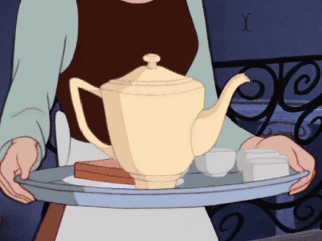 Une personne tenant un plateau avec une grande théière jaune, une petite tasse et un sucrier, rappelant des scènes des films Disney. L’arrière-plan est légèrement flou.