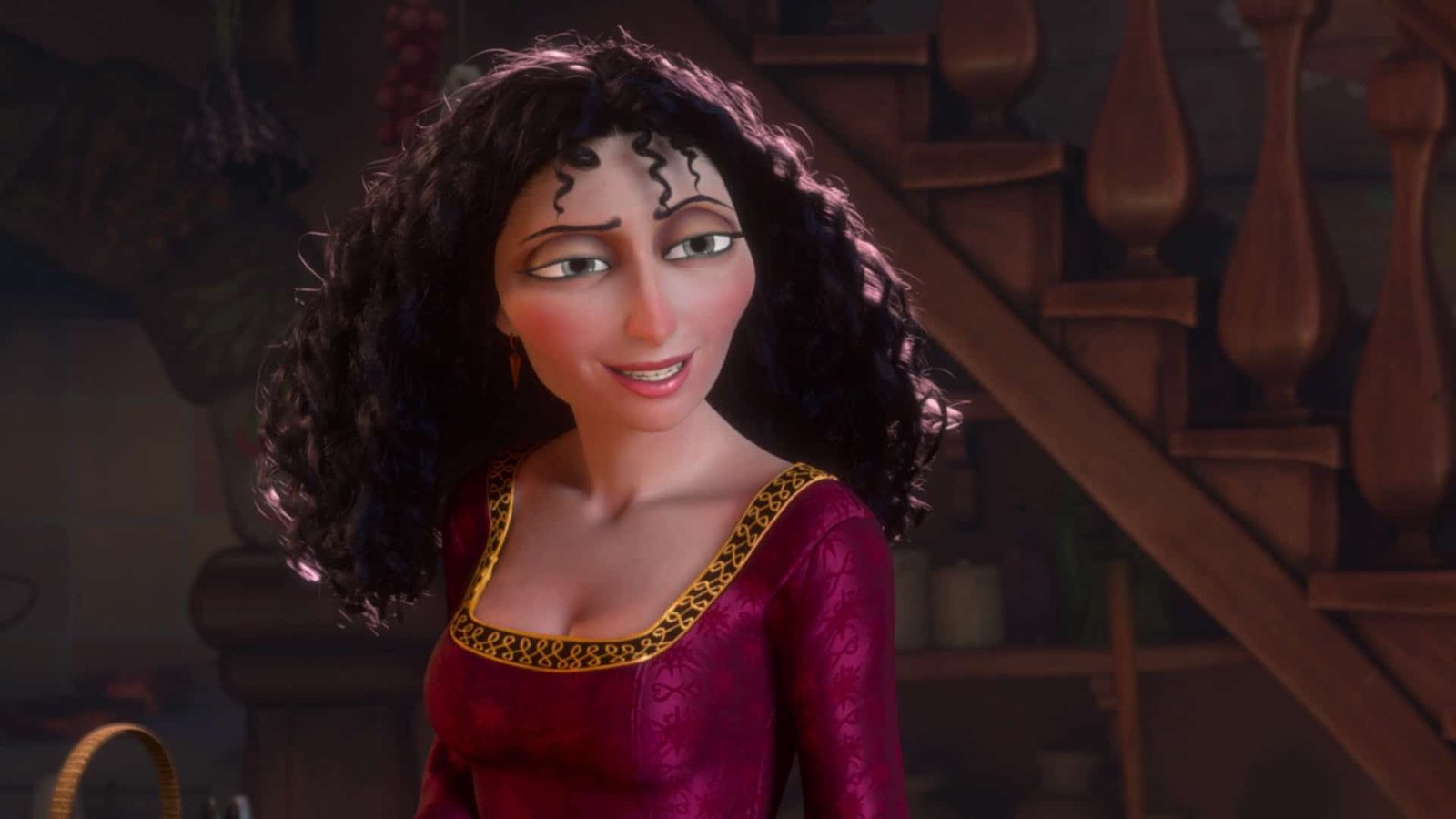 Un personnage Disney animé en 3D avec des cheveux noirs bouclés et une robe rouge, souriant chaleureusement dans une pièce confortable et faiblement éclairée avec un escalier en bois en arrière-plan.