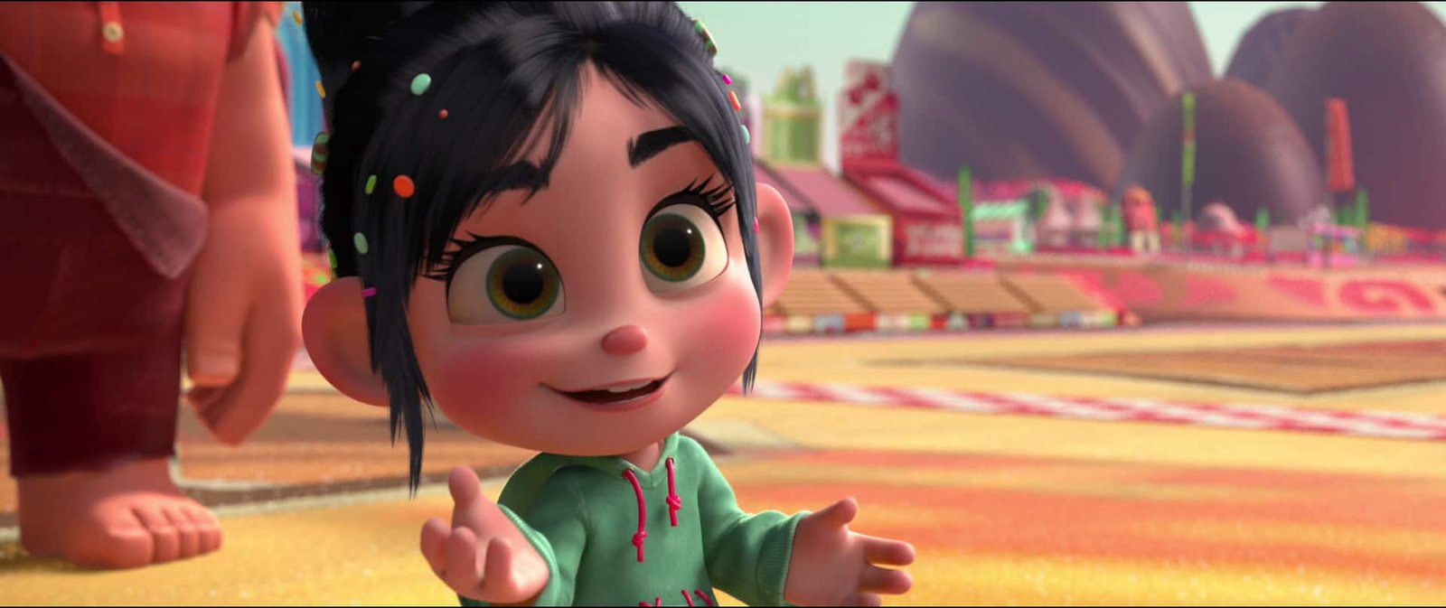 Personnage animé, une jeune fille aux cheveux foncés et à capuche verte, debout avec une expression enjouée et les mains tendues dans un environnement coloré sur le thème de Disney.