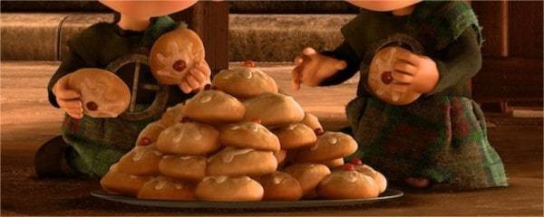 Deux enfants animés vêtus de robes vertes tiennent de gros biscuits devant une pile d'autres biscuits Disney Films sur une assiette, avec un fond confortable et chaleureux suggérant un décor de cuisine.