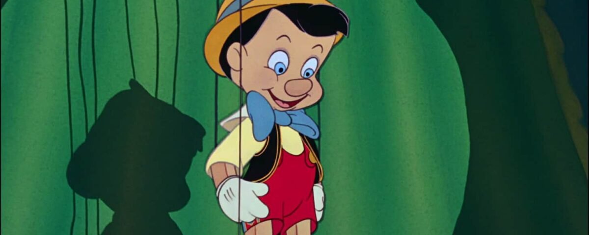 Pinocchio, un garçon marionnette en bois avec un nœud papillon bleu et un chapeau jaune, se tient dans une forêt, souriant, avec son ombre projetée sur un rocher derrière lui.