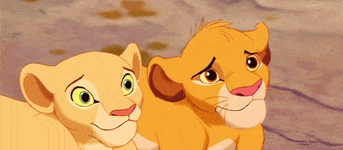 Image animée du film "Le Roi Lion" de deux jeunes lions, un doré et un plus clair, avec des expressions de curiosité et de surprise alors qu'ils regardent attentivement quelque chose.