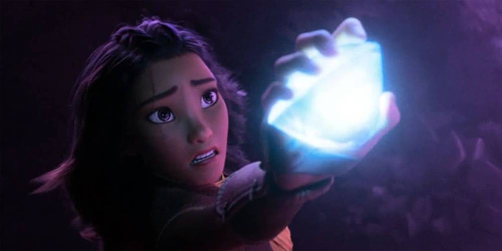 Une jeune fille animée aux cheveux noirs semble étonnée alors qu'elle tient dans sa main un orbe bleu brillant, illuminé par sa lumière dans un décor sombre et violet inspiré de "Raya et le D