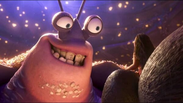Image animée montrant un monstre violet à trois yeux avec des dents éparses souriant et semblant émerveillé par les particules lumineuses qui l'entourent dans un décor Disney sombre et mystique.