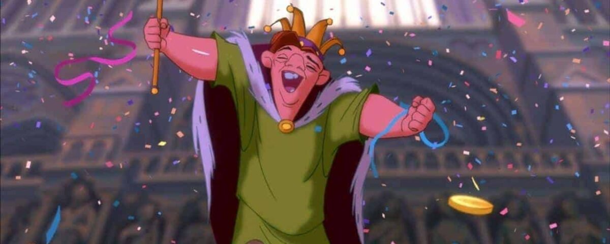 Personnage animé Quasimodo, le bossu de Notre-Dame, tenant joyeusement un sceptre et coiffé d'une couronne, entouré de confettis dans un décor de cathédrale.
