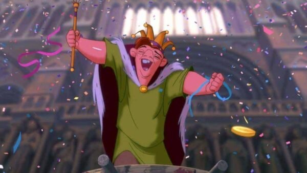Personnage animé Quasimodo, le bossu de Notre-Dame, tenant joyeusement un sceptre et coiffé d'une couronne, entouré de confettis dans un décor de cathédrale.