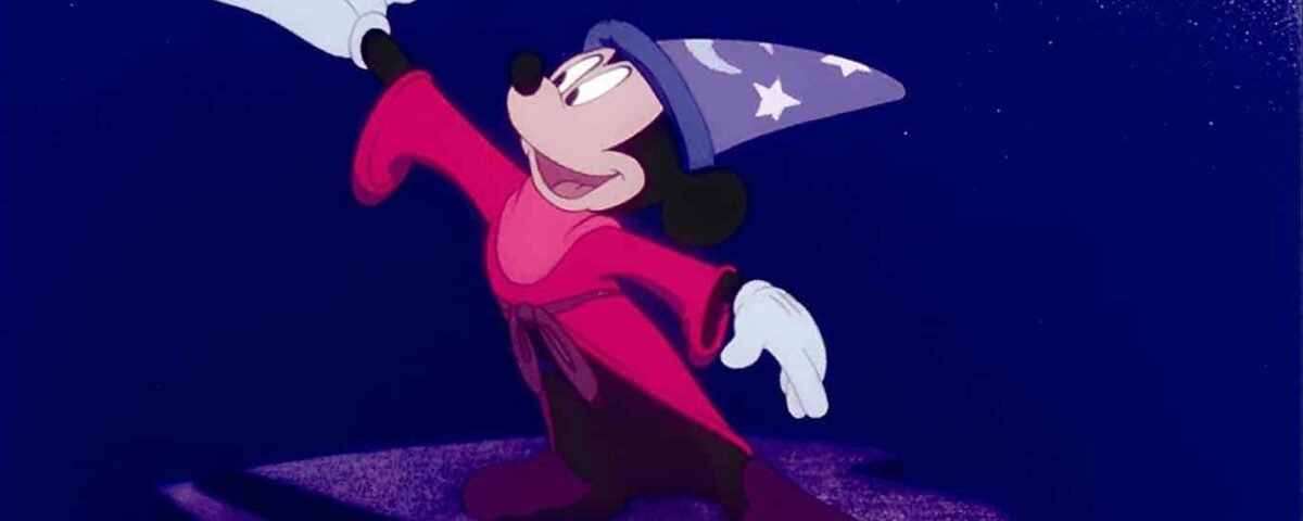 Souris, habillée en apprenti sorcier avec une robe rouge et un chapeau bleu avec des étoiles blanches, se tient sur une plate-forme de pierre sous un ciel étoilé, agitant dramatiquement la main.