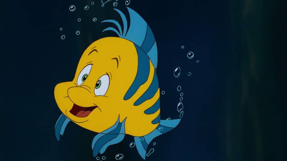 Un poisson coloré de dessin animé Disney avec des rayures bleues et jaunes sourit alors qu'il nage sous l'eau, entouré de petites bulles.