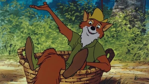 Renard animé portant une chemise verte et un chapeau jaune, allongé dans un panier dans un décor de forêt Disney, faisant des gestes avec un bras levé.