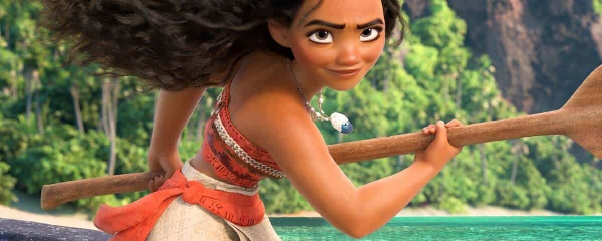 Personnage animé Vaiana, aux longs cheveux bouclés, tenant une pagaie sur une plage, avec des arbres tropicaux et de l'eau bleue en arrière-plan.