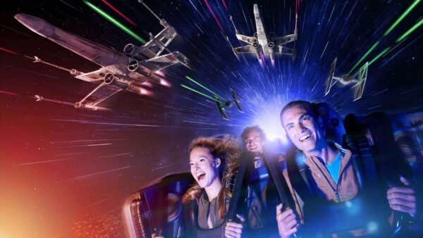 Trois personnes profitant d'une aventure spatiale dynamique en réalité virtuelle à Disneyland Paris, riant et saisissant leurs poignées alors que les vaisseaux spatiaux se battent autour d'eux sur fond d'étoiles et de faisceaux laser colorés.