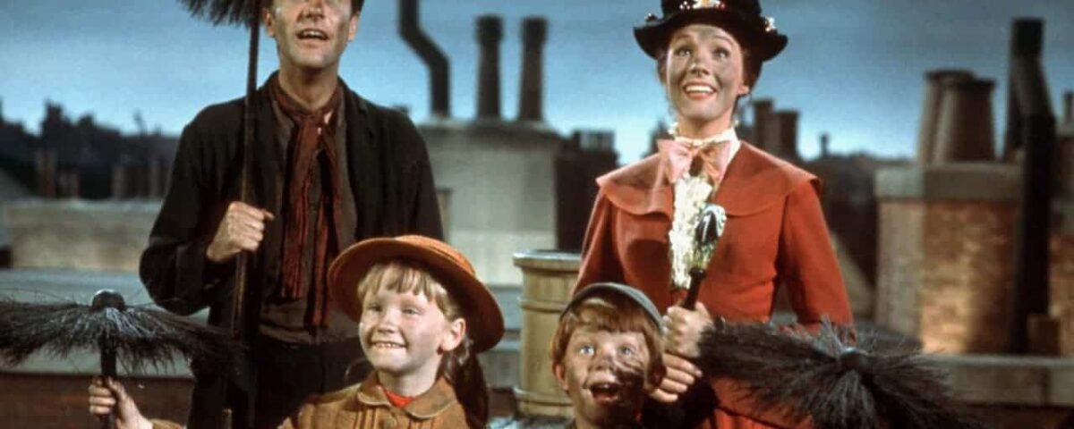 Une scène du film musical "Mary Poppins" mettant en vedette la nounou Mary Poppins et Bert avec deux enfants, tous tenant des brosses de ramoneur, sur fond de cheminées sur les toits.