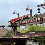Panneau indiquant l'attraction "Indiana Jones et le Temple du Péril" à Disneyland Paris, indiquant un temps d'attente de 5 minutes sous un ciel nuageux.