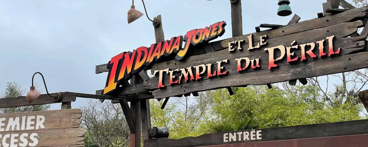 Panneau indiquant l'attraction "Indiana Jones et le Temple du Péril" à Disneyland Paris, indiquant un temps d'attente de 5 minutes sous un ciel nuageux.
