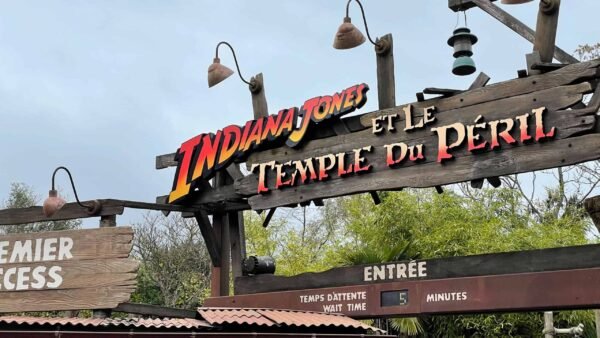 Panneau indiquant l'attraction "Indiana Jones et le Temple du Péril" à Disneyland Paris, indiquant un temps d'attente de 5 minutes sous un ciel nuageux.