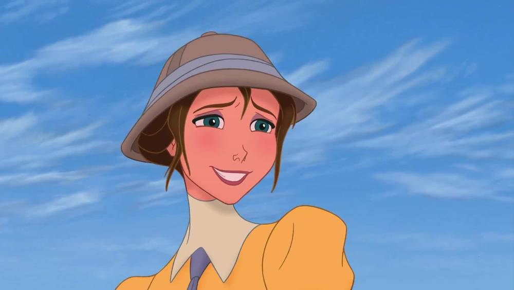 Personnage féminin animé aux cheveux auburn portant un chapeau et une chemise jaune, souriant sur fond d'aventure dans la jungle inspirée du Tarzan d'Edgar Rice Burroughs.