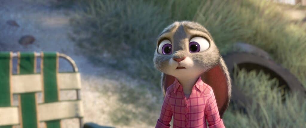 Gros plan d'un lapin de dessin animé du film d'animation Zootopia, avec de grands yeux violets et une chemise à carreaux rose, l'air surpris ou inquiet, sur un fond extérieur avec de la verdure et