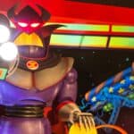 Une figurine robotique colorée au design caricatural, inspirée de Buzz l'Éclair de Toy Story, avec de grands yeux lumineux, un casque diabolique et tenant ce qui semble être un espace