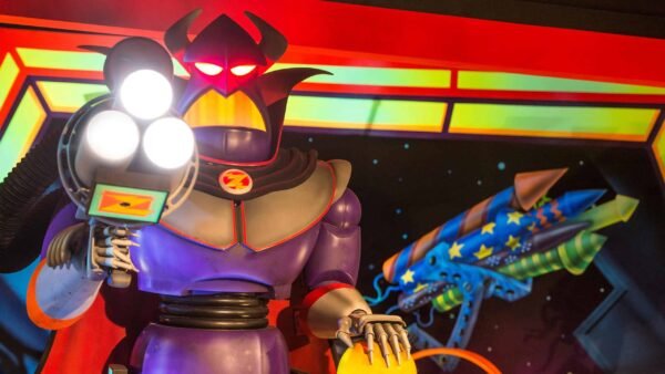 Une figurine robotique colorée au design caricatural, inspirée de Buzz l'Éclair de Toy Story, avec de grands yeux lumineux, un casque diabolique et tenant ce qui semble être un espace