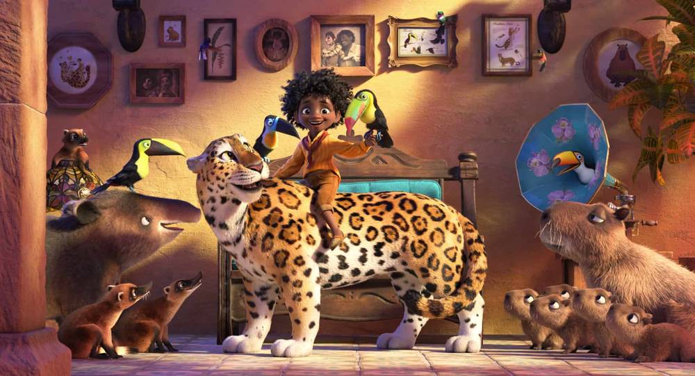 Une joyeuse scène animée du film Disney "Encanto" mettant en scène un jeune garçon aux cheveux bouclés chevauchant un grand léopard tacheté, entouré de divers animaux, dont des oiseaux et des ours, dans une pièce chaleureusement éclairée et remplie de