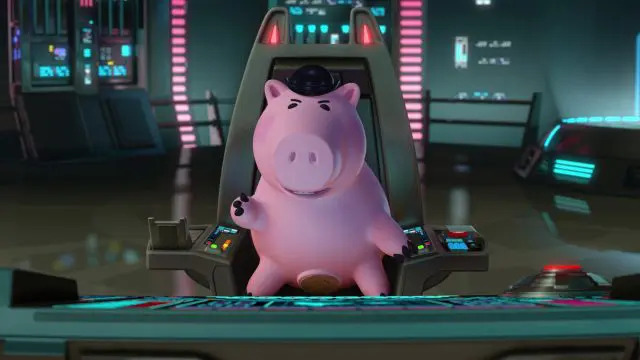 Un cochon de dessin animé assis dans le cockpit d'un vaisseau spatial futuriste, inspiré de "Toy Story", entouré de panneaux de commande et d'écrans lumineux. Le cochon semble confiant et fait des gestes avec son sabot droit.