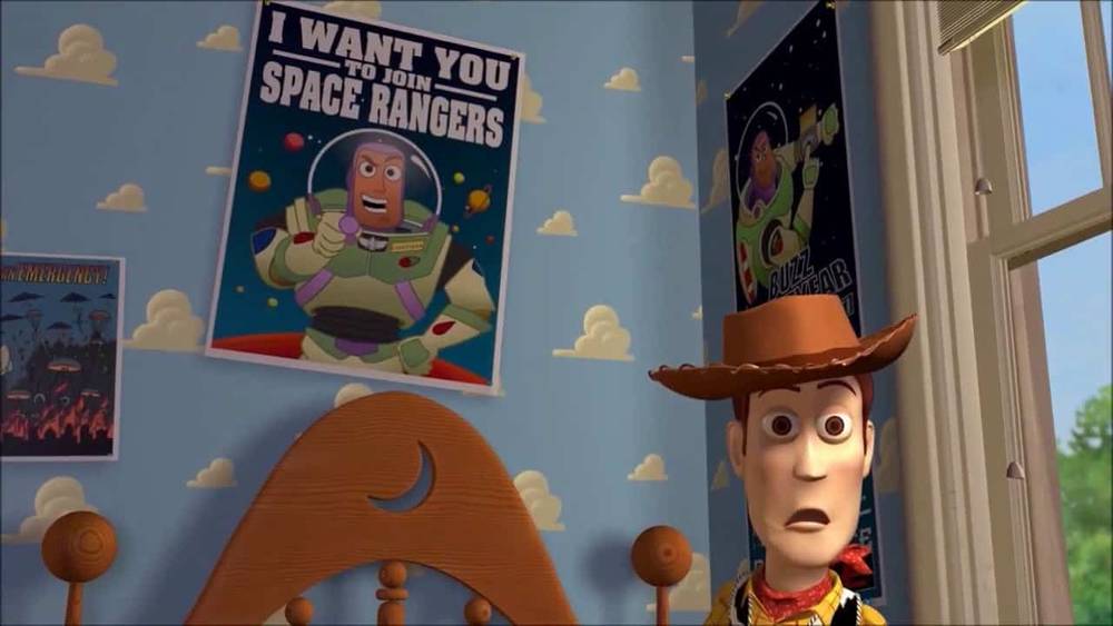 Une image animée en 3D montrant Woody de Toy Story, l'air surpris. En arrière-plan, une affiche représente Buzz l'Éclair avec le texte "Je te veux pour Space Rangers.