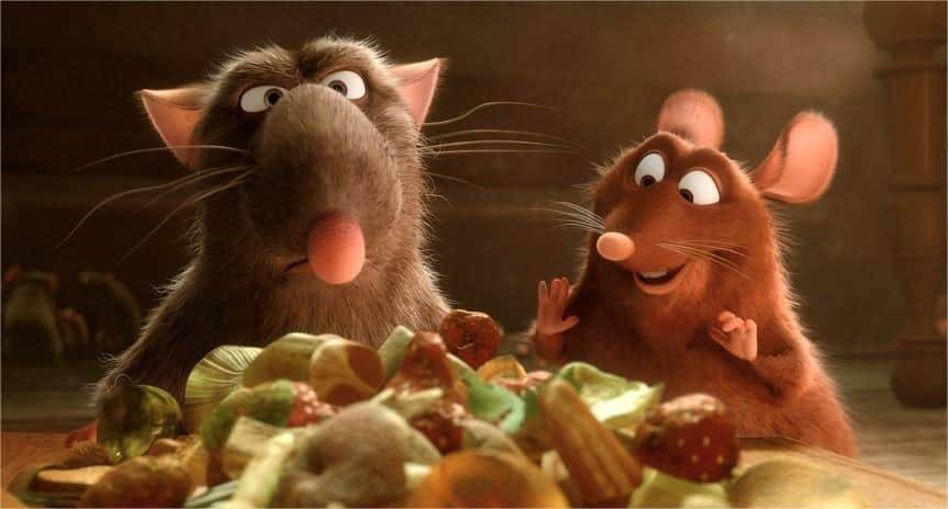 Deux rats animés, un gris et un brun, regardent avec enthousiasme une pile de divers aliments colorés, dont des fruits et de la ratatouille, dans un environnement chaleureusement éclairé.