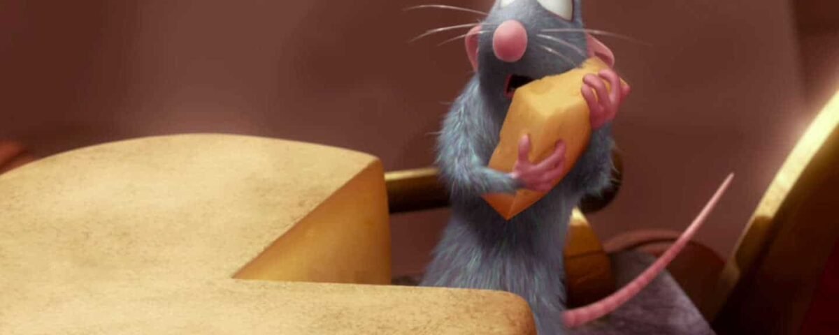Une image de dessin animé de Rémy, un petit rat bleu-gris du film "Ratatouille", tenant joyeusement un morceau de fromage à deux mains alors qu'il se tient debout sur un comptoir de cuisine entouré d'ingrédients.