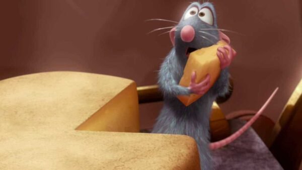 Une image de dessin animé de Rémy, un petit rat bleu-gris du film "Ratatouille", tenant joyeusement un morceau de fromage à deux mains alors qu'il se tient debout sur un comptoir de cuisine entouré d'ingrédients.