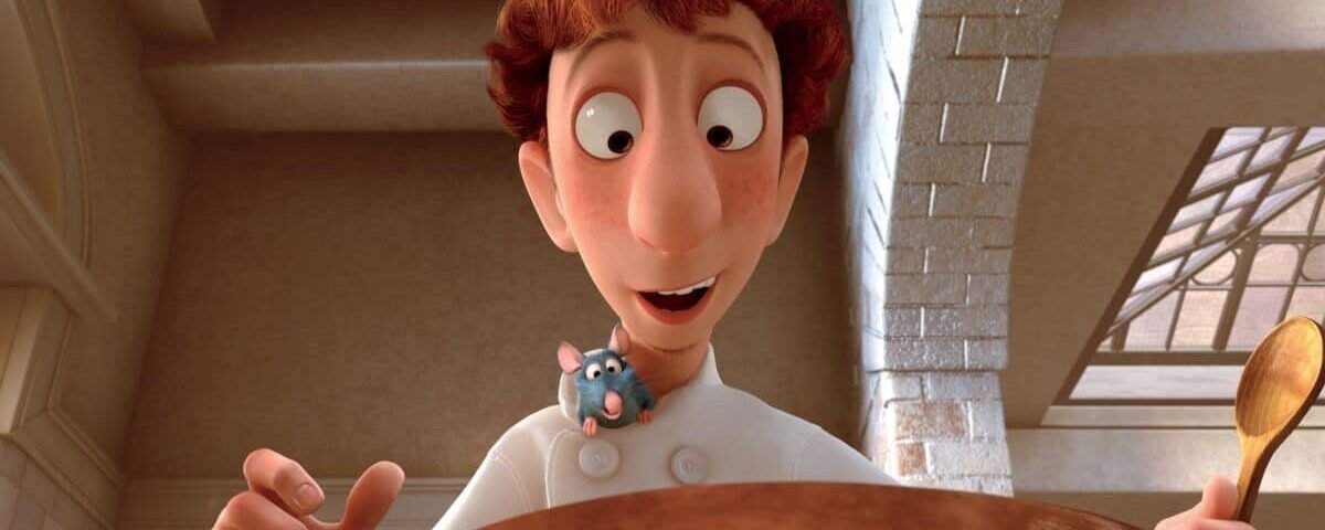 Un personnage animé, un jeune chef aux cheveux roux, sourit en tenant une cuillère en bois au-dessus d'une grande marmite de ratatouille, avec un petit rat bleu qui sort de sa veste de chef
