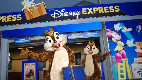Deux personnages costumés ressemblant à Chip et Dale se tiennent devant un magasin Disneyland Paris Express, orné de décorations et d'enseignes sur le thème Disney.