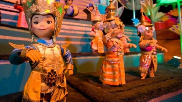 Une exposition colorée de marionnettes animées vêtues de costumes traditionnels asiatiques, avec une marionnette au premier plan pointée vers l'avant, sur un fond vibrant et festif conçu comme un puzzle.