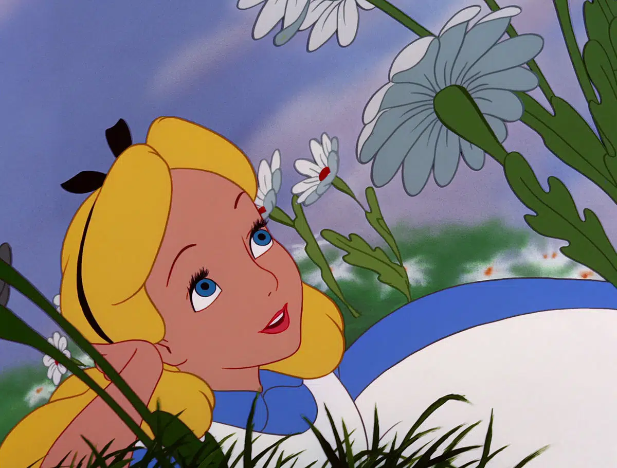 Image animée d'Alice d'Alice au pays des merveilles, allongée dans l'herbe et levant les yeux, avec de grandes marguerites et un ciel bleu en arrière-plan.