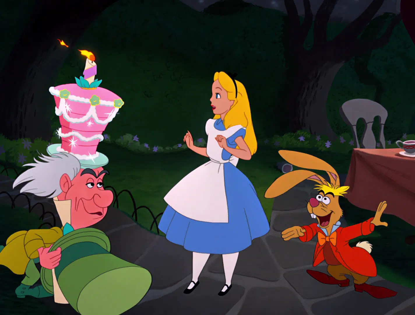 Alice au pays des merveilles est surprise lorsque le Chapelier Fou et le Lièvre de Mars lui présentent un gâteau d'anniversaire allumé dans un décor forestier fantaisiste la nuit.