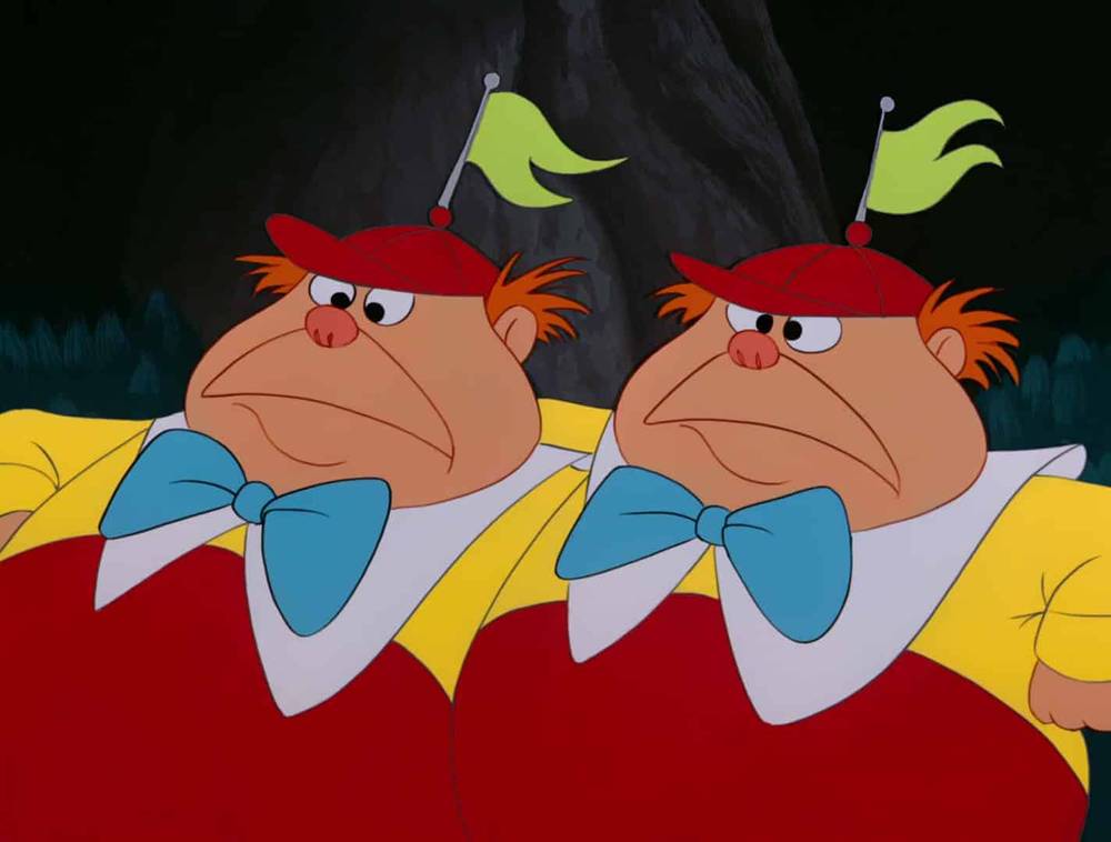 Deux personnages animés, ressemblant à des jumeaux volumineux d'Alice au pays des merveilles, vêtus de hauts rouges et de chemises jaunes avec des nœuds papillon bleus et des chapeaux à antennes vertes, se tenant côte à côte avec des expressions grincheuses.